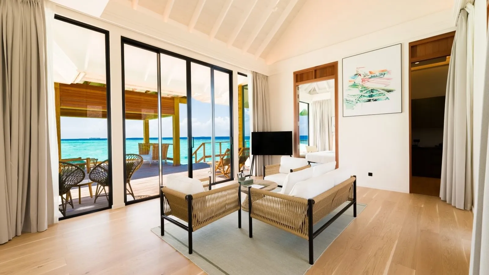 The living room of the Thila residence, its glass doors onto the deck and the sea.