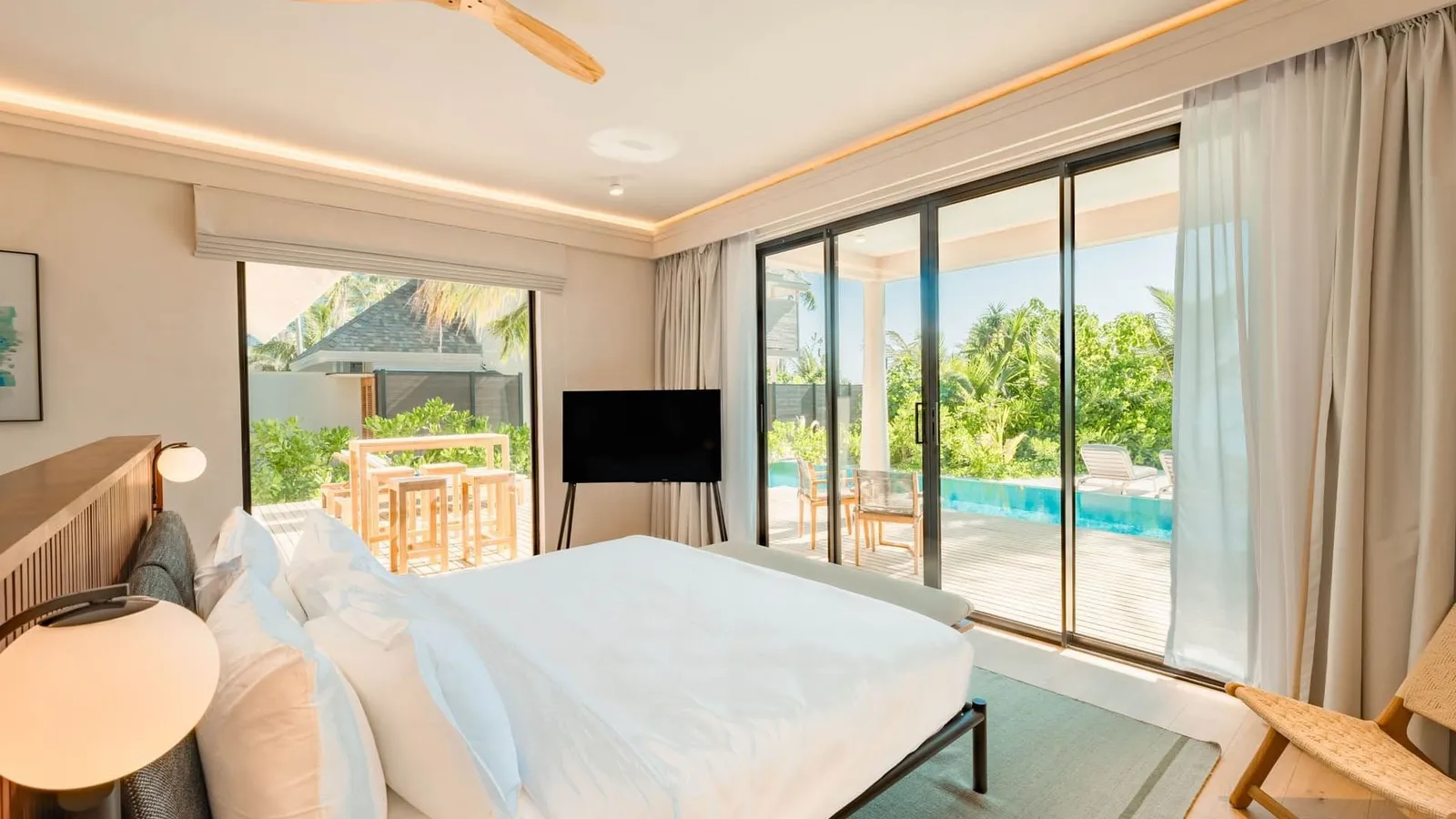 A bedroom in a 2-Bedroom Beach Pool Villa, its glass doors onto the pool and garden.