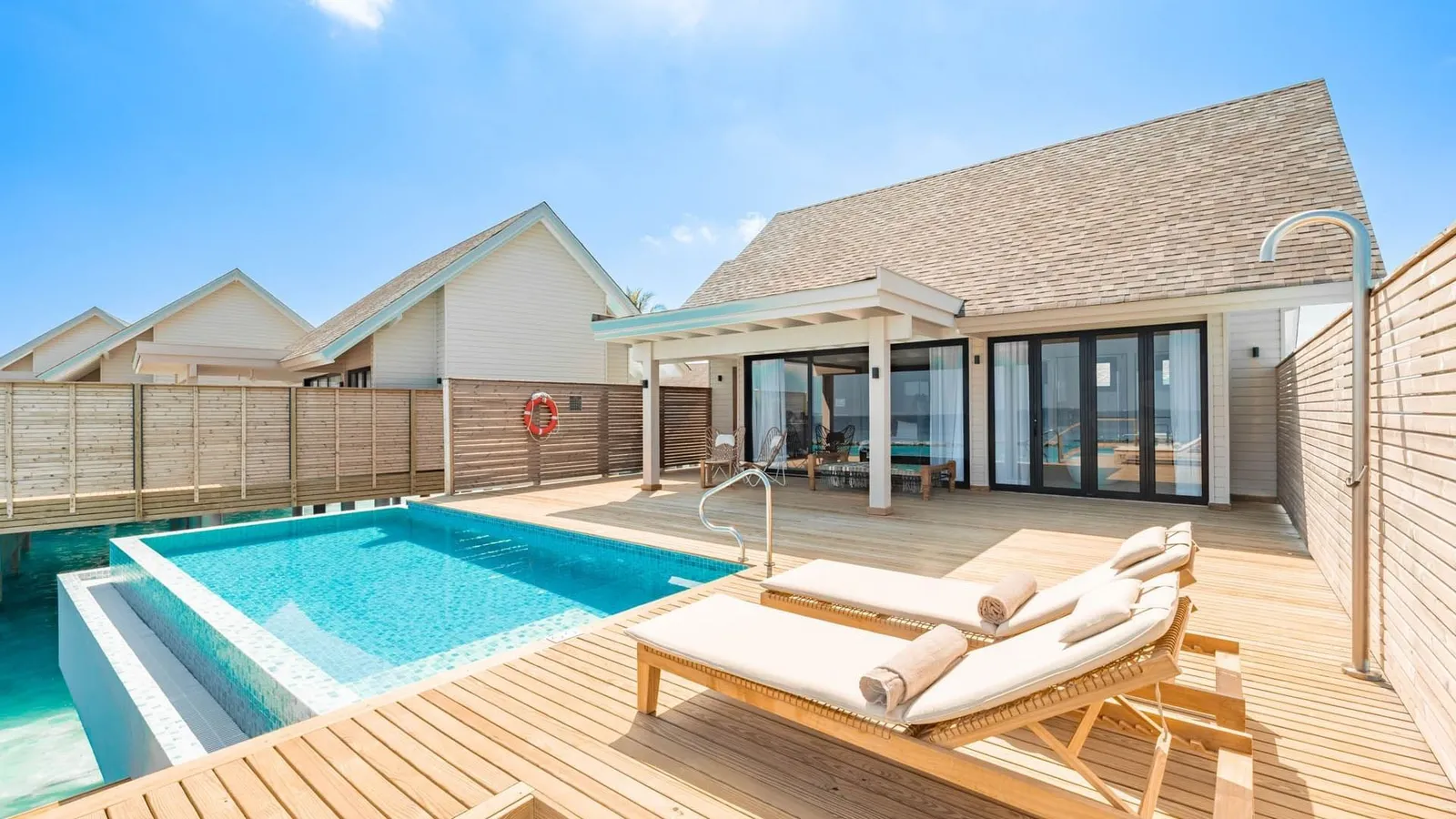 A Water Pool Villa’s deck, with the pool and loungers in front of the glass doors.