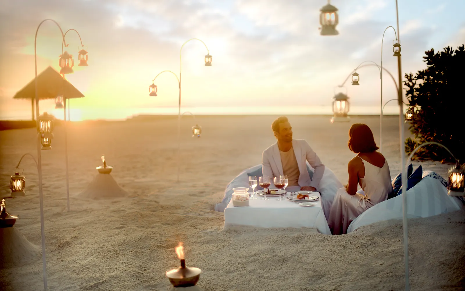 Una cena per 2 sulla sabbia al tramonto, fra le lanterne accese e le fiaccole.