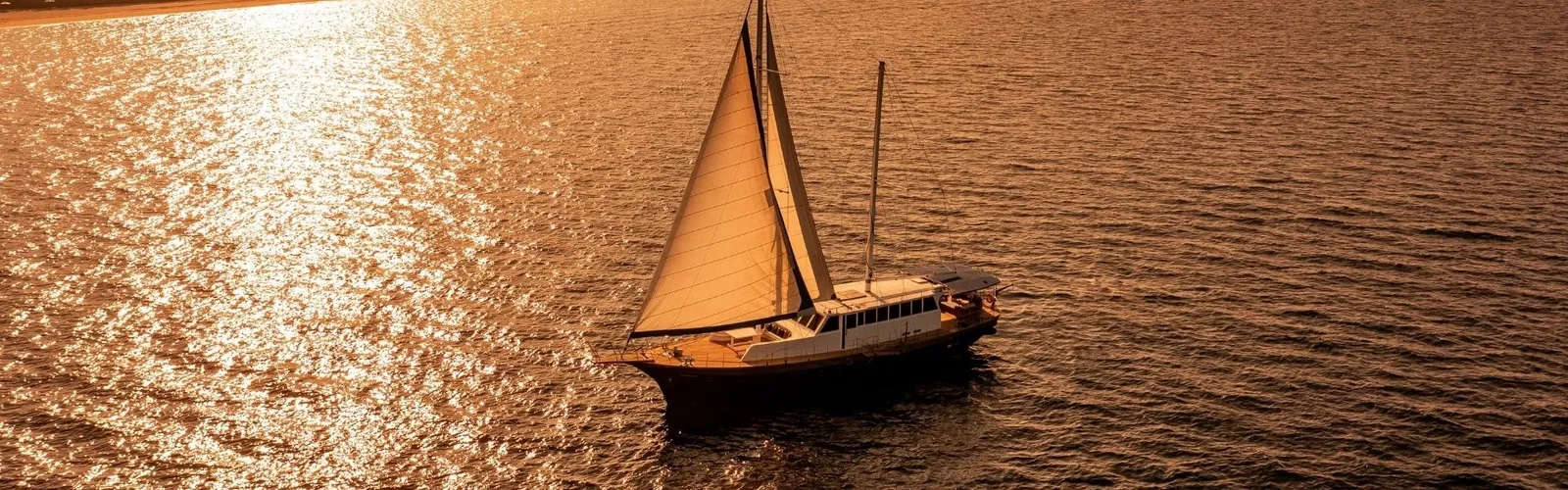 A sailing boat at sunset on a golden sea