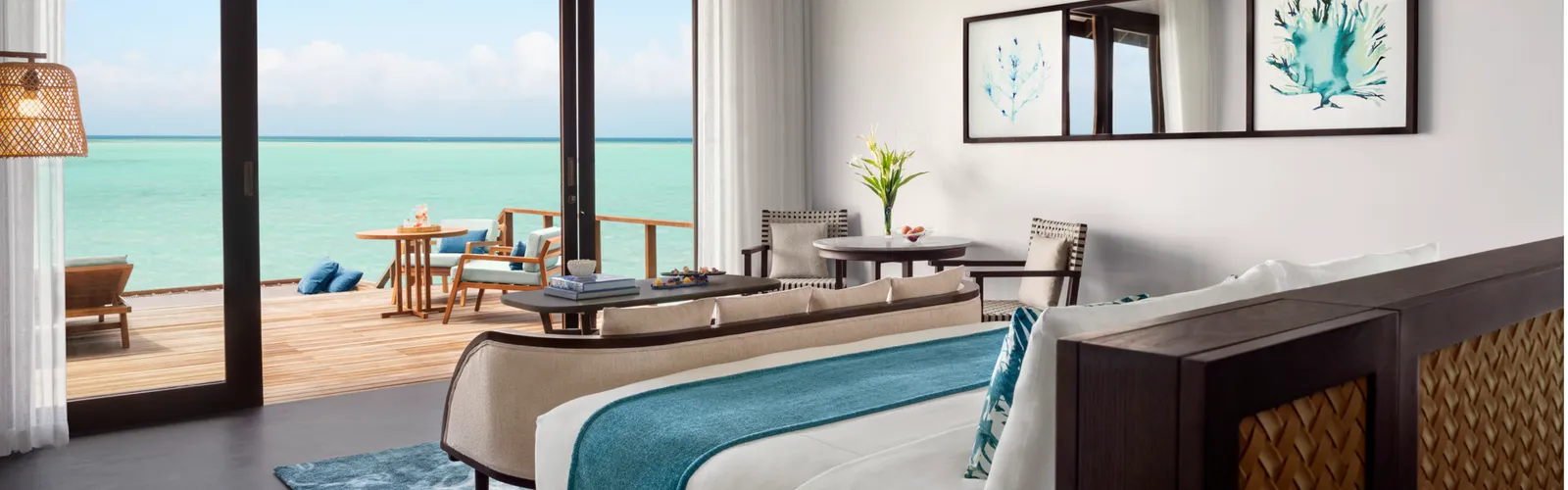 La camera della Deluxe Over Water Pool Villa, il letto e le vetrate verso l’esterno