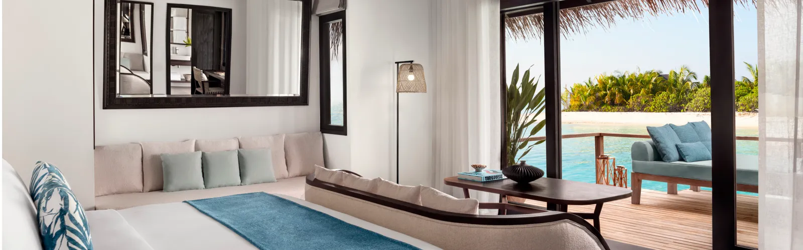 La camera della Deluxe Over Water Villa, il letto e le vetrate verso l’esterno