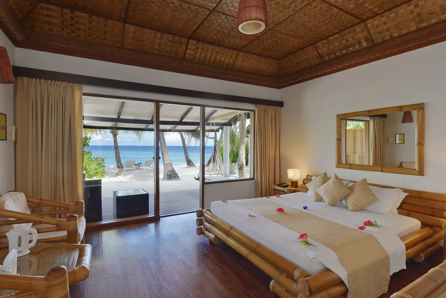 La camera di un Superior Beach Bungalow, con il letto di bambù e la porta a vetri aperta sulla spiaggia.