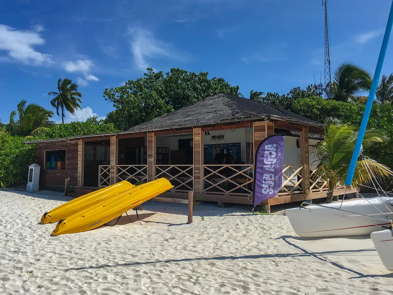 Il centro immersioni sulla spiaggia, con i kayak gialli sulla sabbia e una vela appoggiata accanto.
