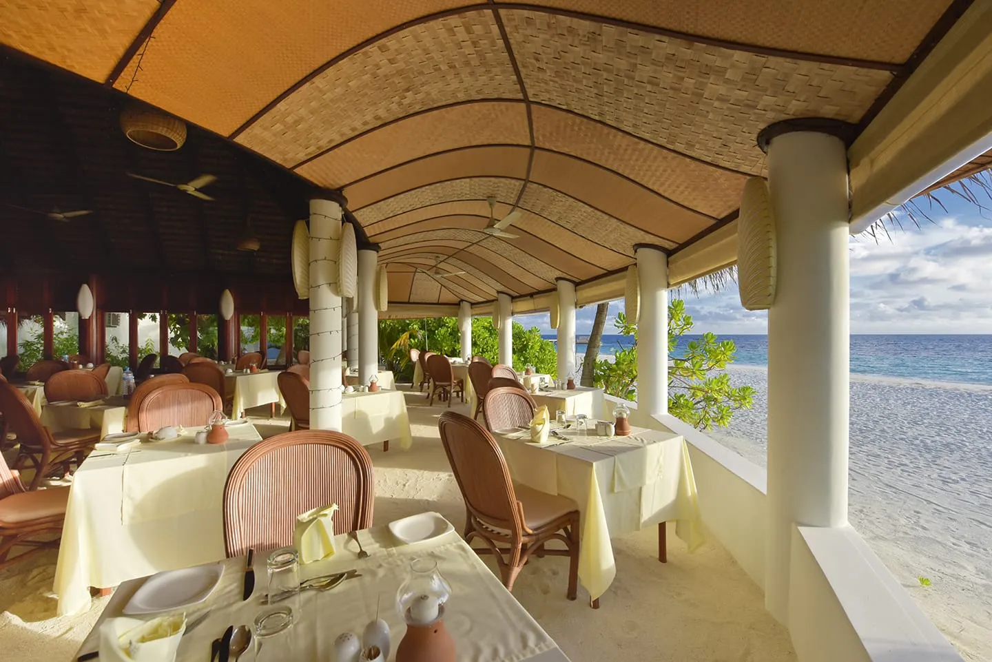 La sala del Dolphin Restaurant, con le tovaglie bianche, il soffitto di paglia e la sabbia che arriva fino ai tavoli.