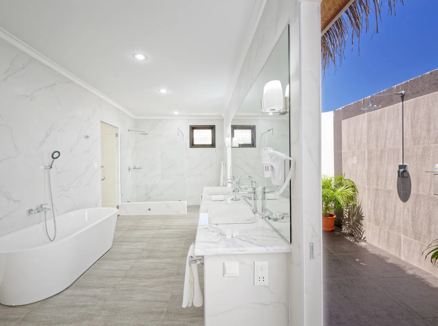 Il bagno di un Premium Water Bungalow, con la vasca libera, il doppio lavabo e la doccia all’aperto.