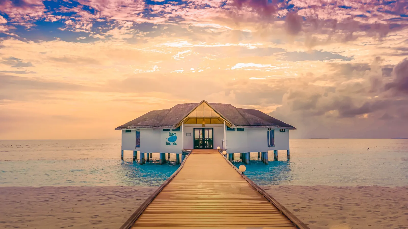 La Duny Thai Spa in fondo al suo pontile, sull’acqua, sotto un cielo rosa al tramonto.