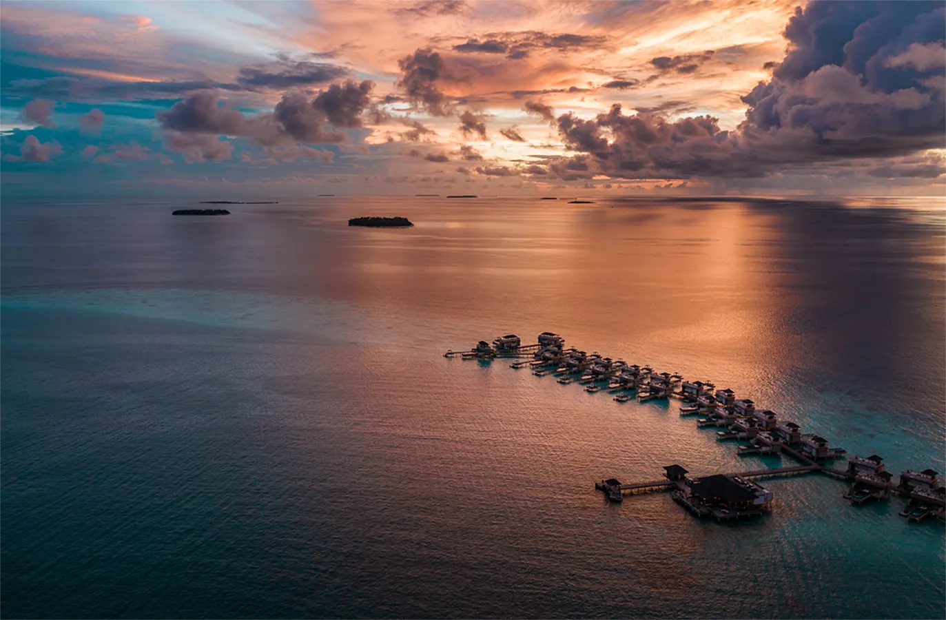 The InOcean villas at sunset, a dark line on water mirroring a pink and orange sky.