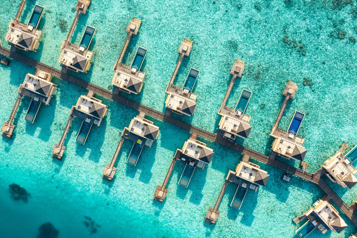 The InOcean villas from above, in 2 rows along the boardwalk, their pools over the pale lagoon.