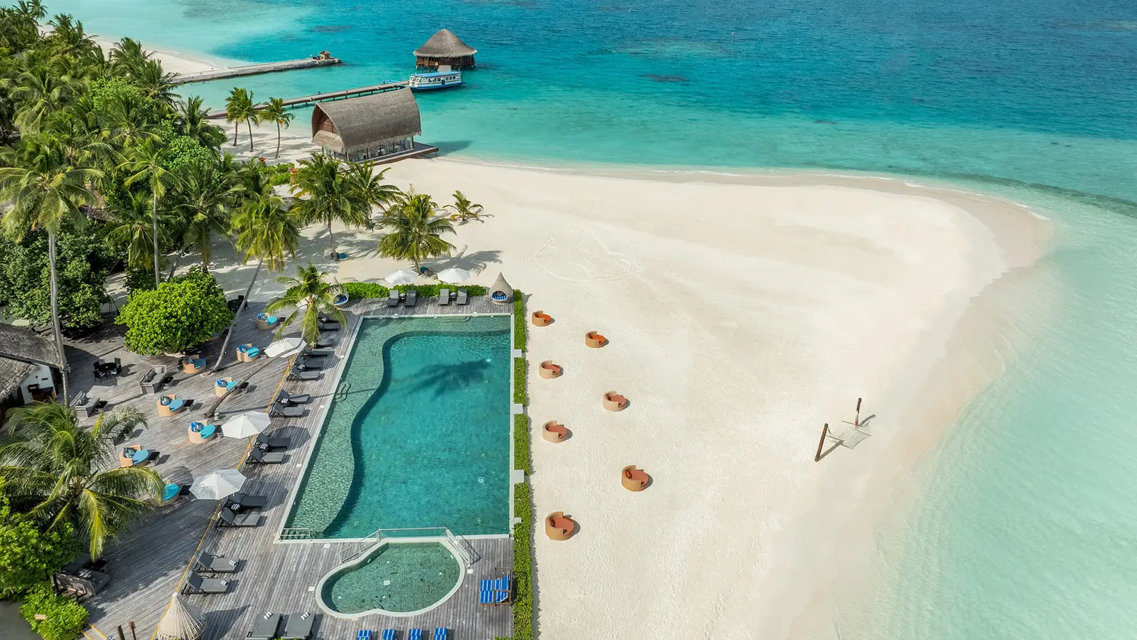 The main pool and the children’s pool from above, beside the beach, with loungers and parasols.