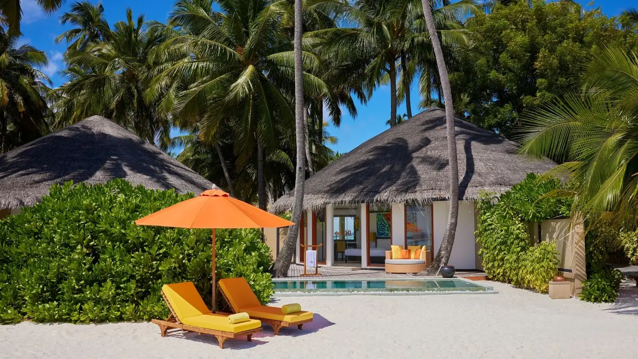 A Beachfront Infinity Pool Villa’s pool in front of the thatched villa, with 2 yellow loungers.