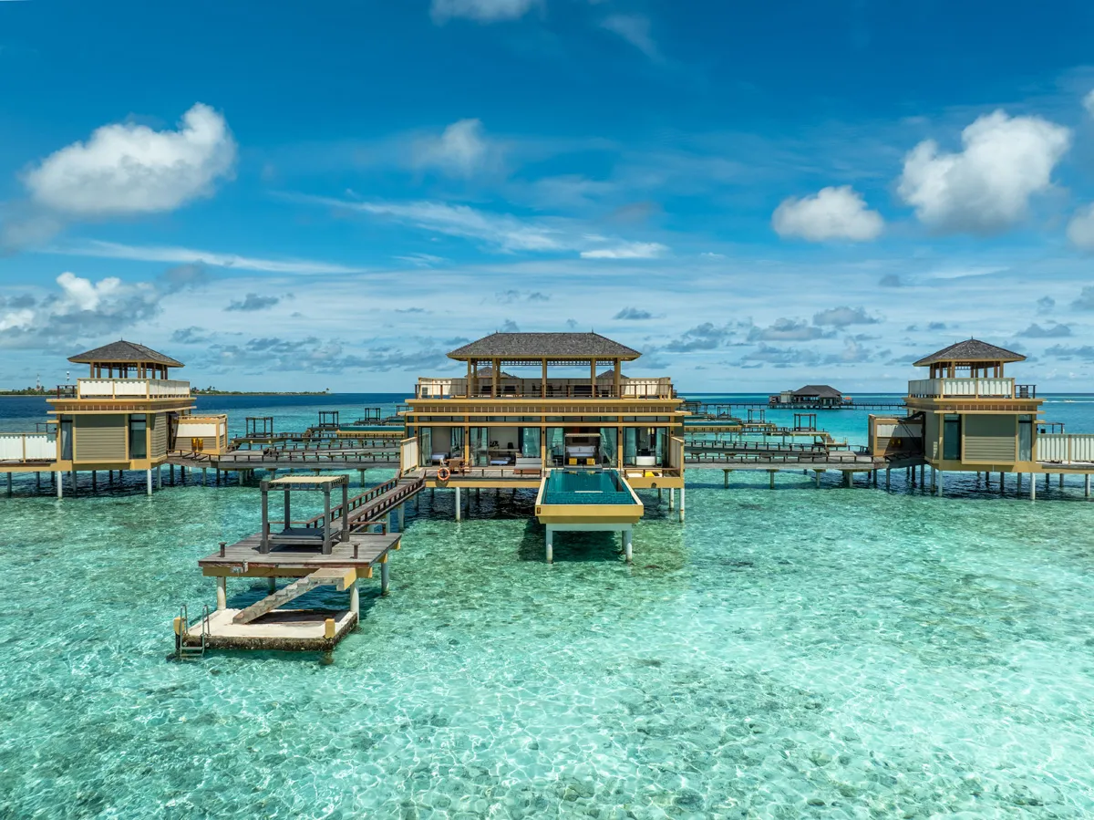 Deluxe InOcean Pool Villas over the lagoon, with their decks, pools and pagoda roofs against the sky.