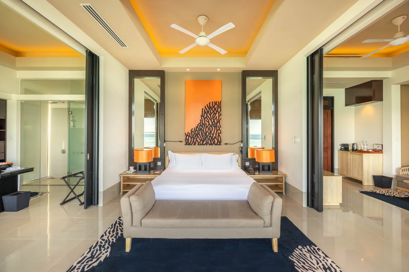An InOcean villa bedroom, with its king bed, a sofa at the foot of the bed and mirrors either side.