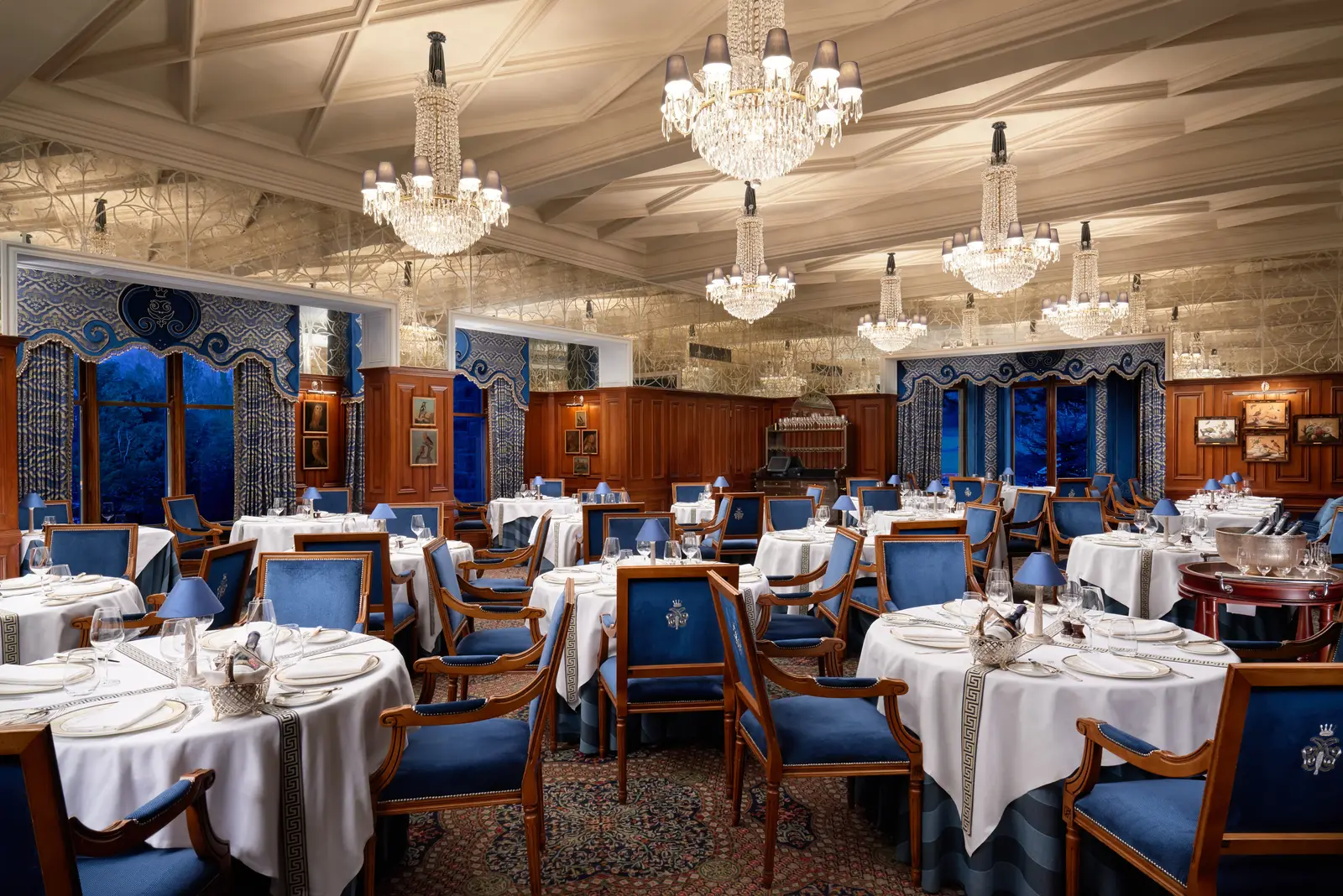 The George V Dining Room: crystal chandeliers and blue chairs under the panelled ceiling