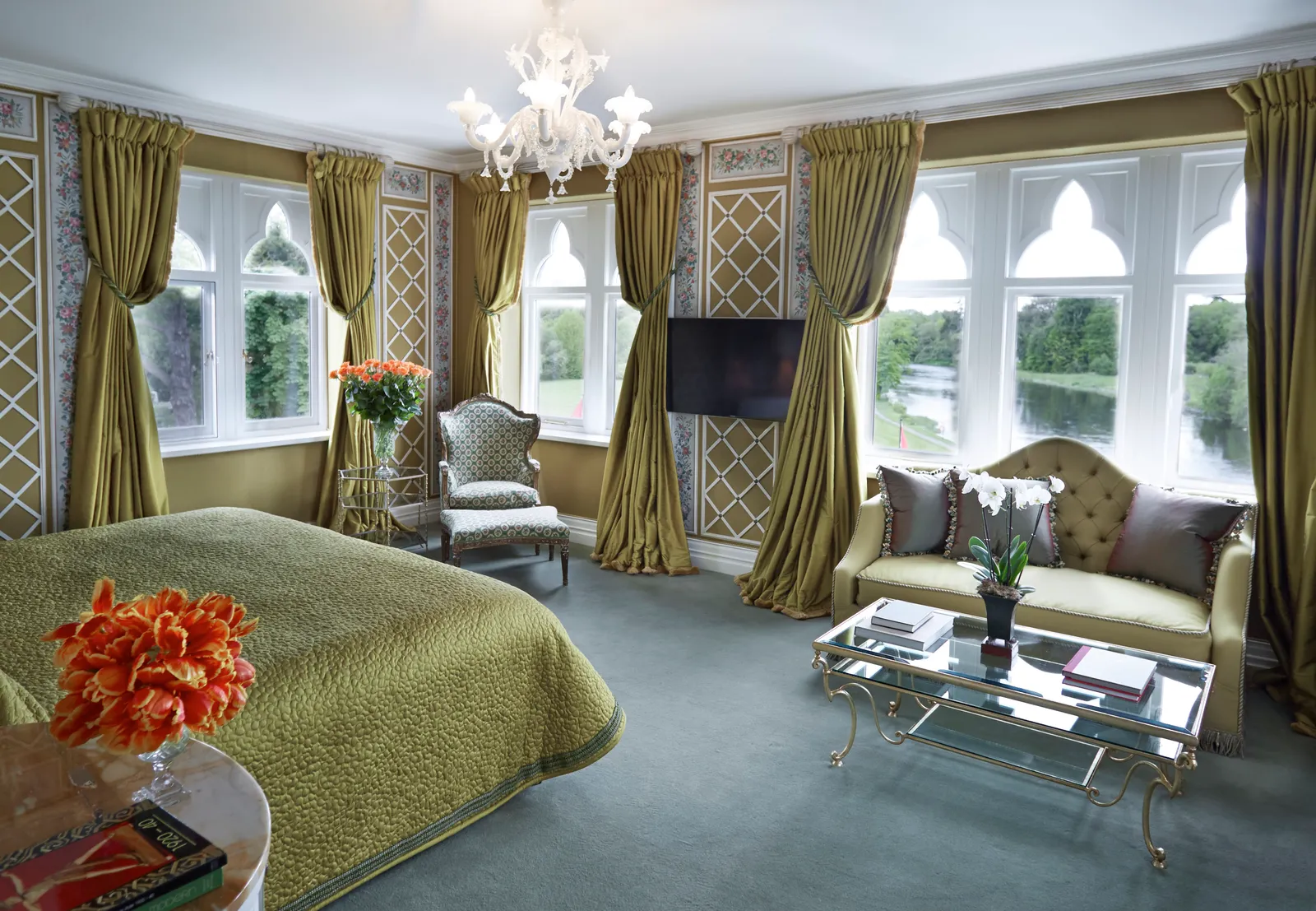 A Deluxe Room: a sage-green bed, a sofa and 2 windows over the estate