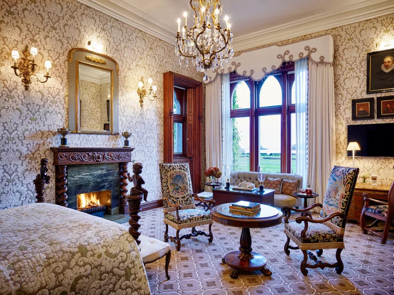 The Kennedy Suite: the bed in the foreground and armchairs by the lit fireplace