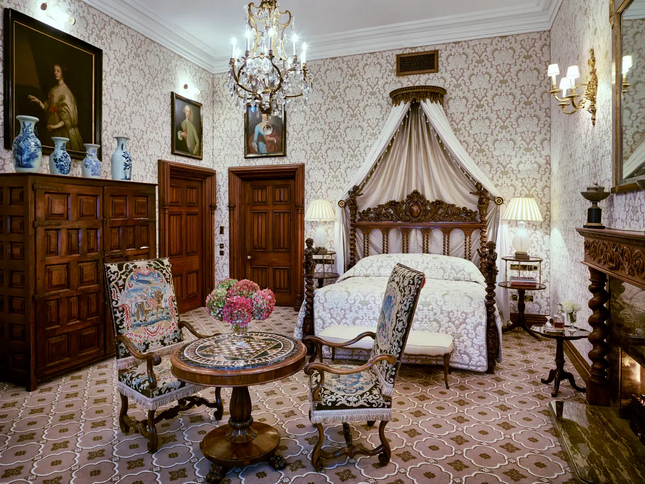 A Stateroom: a crowned canopy bed, a carved chest and a round table