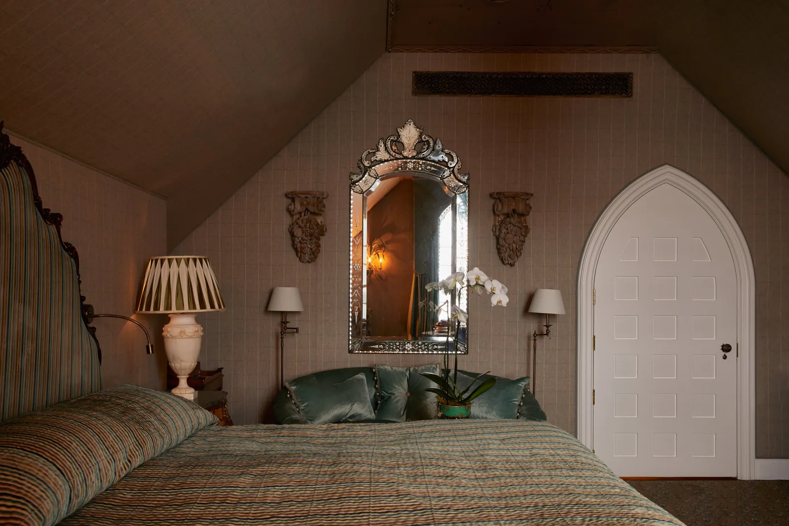 The Boathouse bedroom: a king bed under the sloping roof and an arched door