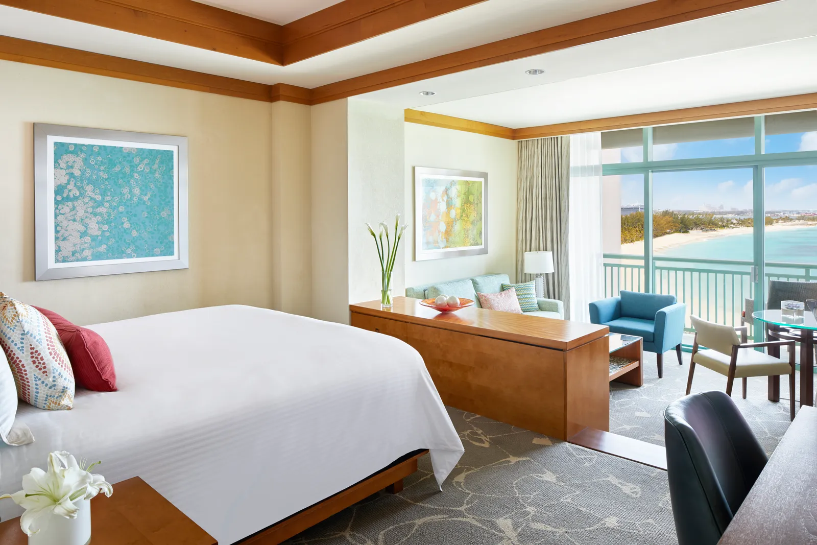 A suite at The Cove with a king bed, a step-down sitting area with a sofa and a window onto the beach.
