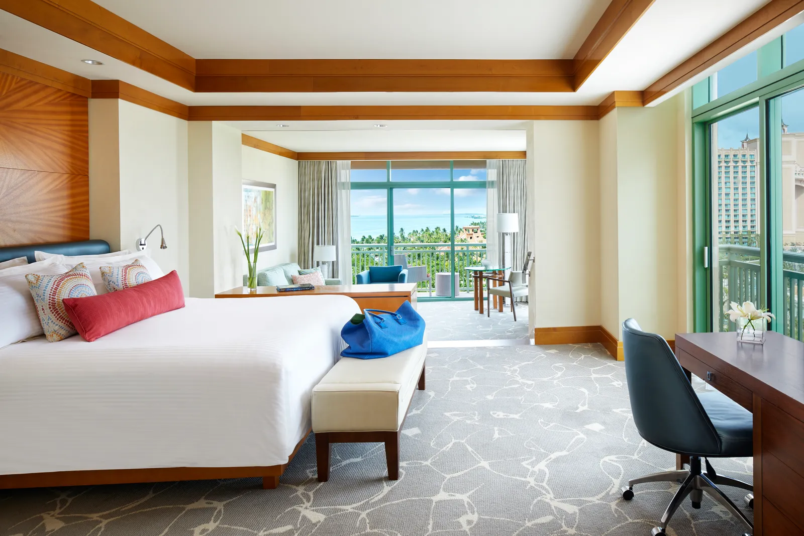 An Indigo suite at The Cove: a king bed with bright cushions, a desk and, a step down, the sitting area by the window.