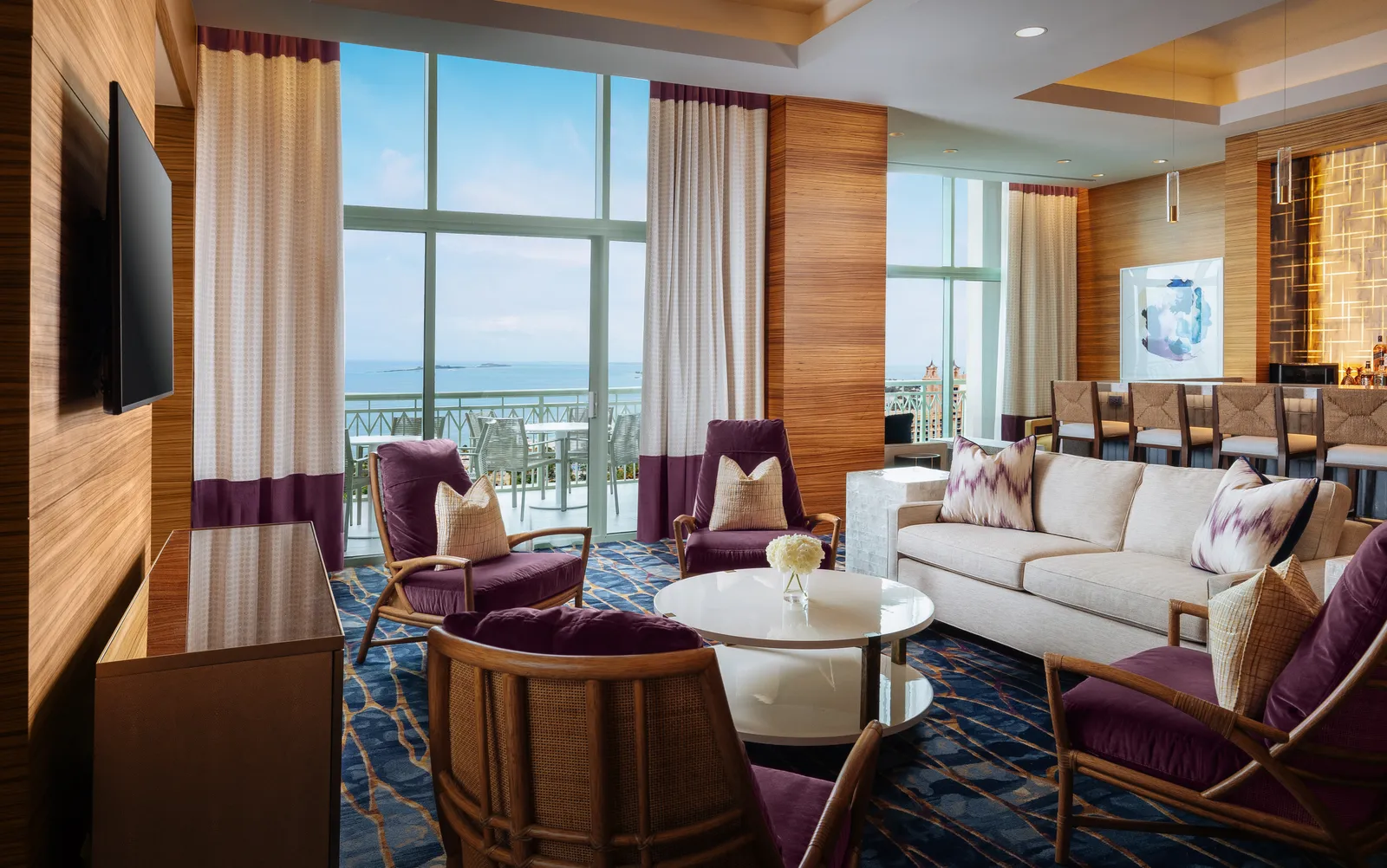 The Lapis club lounge at The Cove, with purple armchairs, timber walls and full-height windows over the sea.