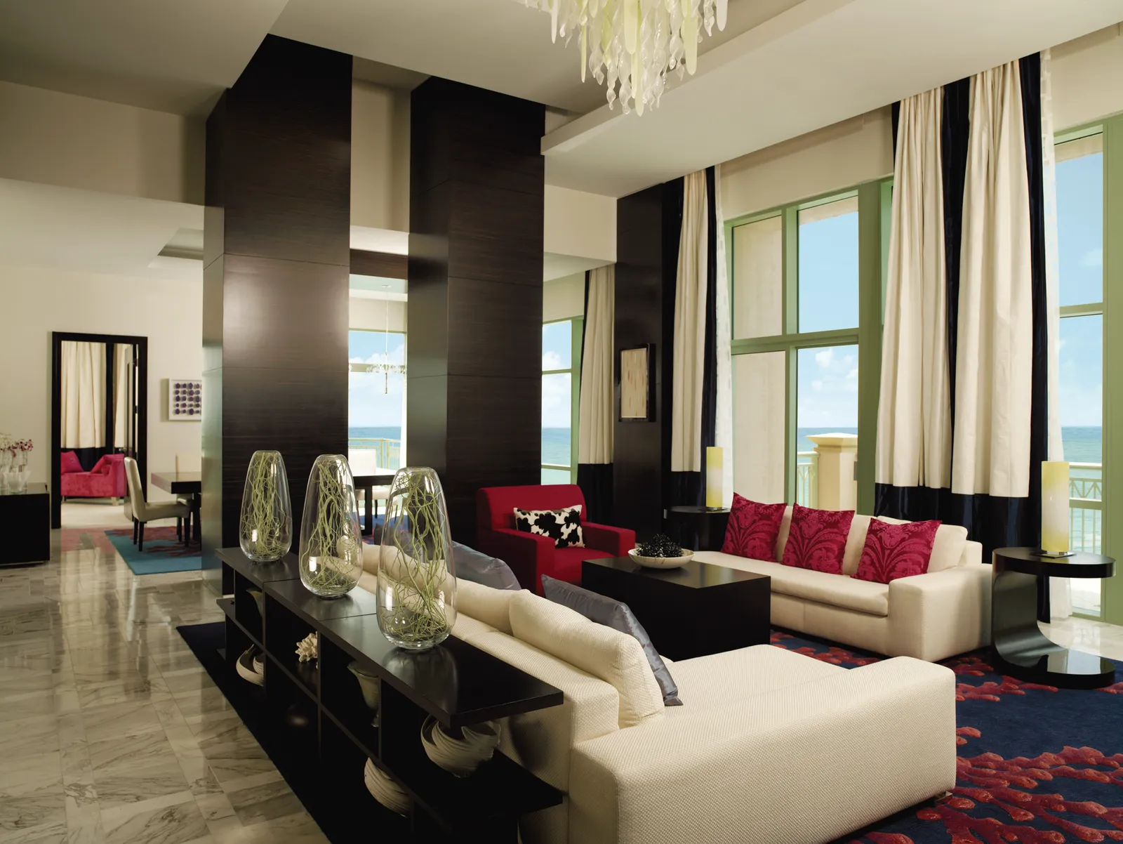 The living room of a penthouse at The Cove, with a marble floor, pale sofas and tall windows with striped curtains.