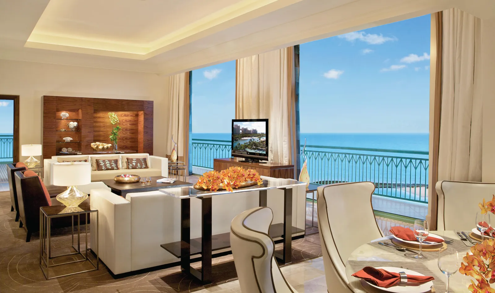 The living room of a penthouse at The Reef, with pale sofas, a laid table and a terrace open to the sea.