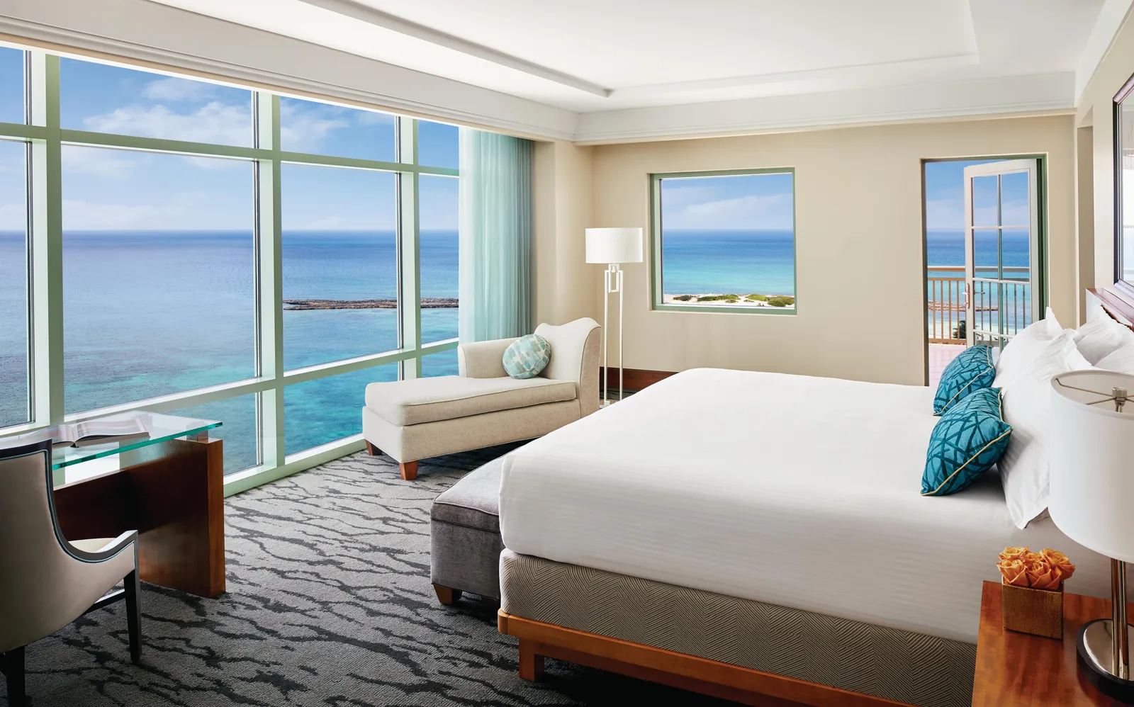 The bedroom of a Topaz suite, the king bed facing a corner window over open sea.