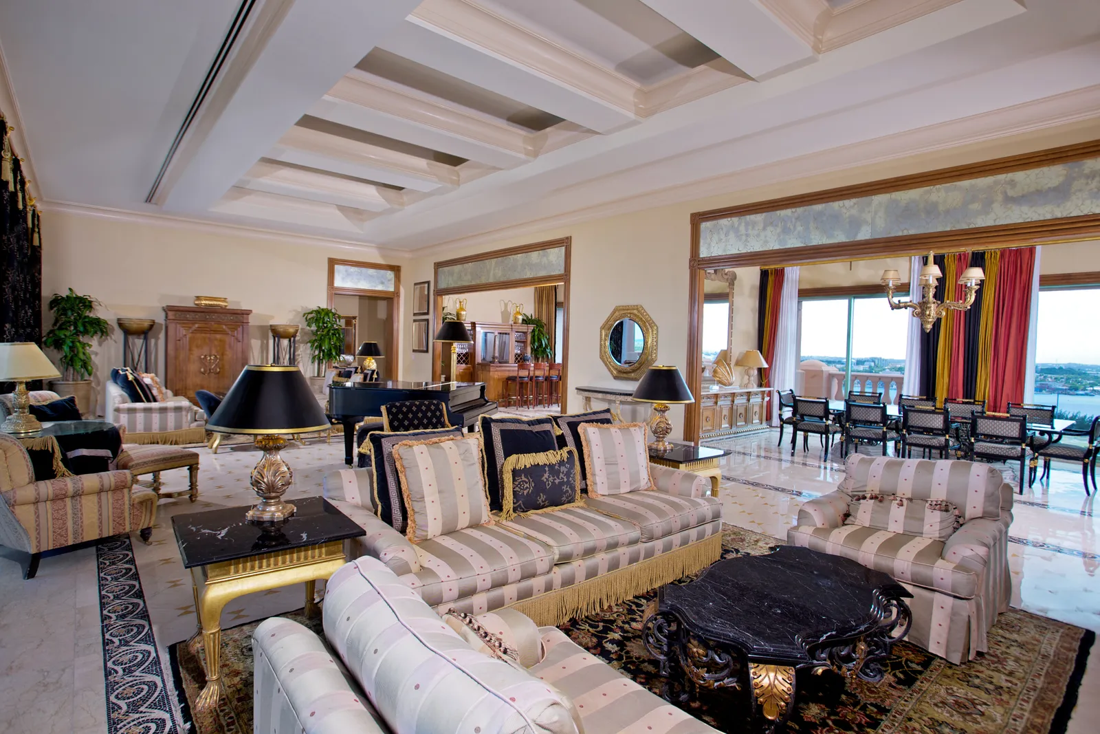 The Bridge Suite’s drawing room: striped sofas, a grand piano, a long dining table and a coffered ceiling.