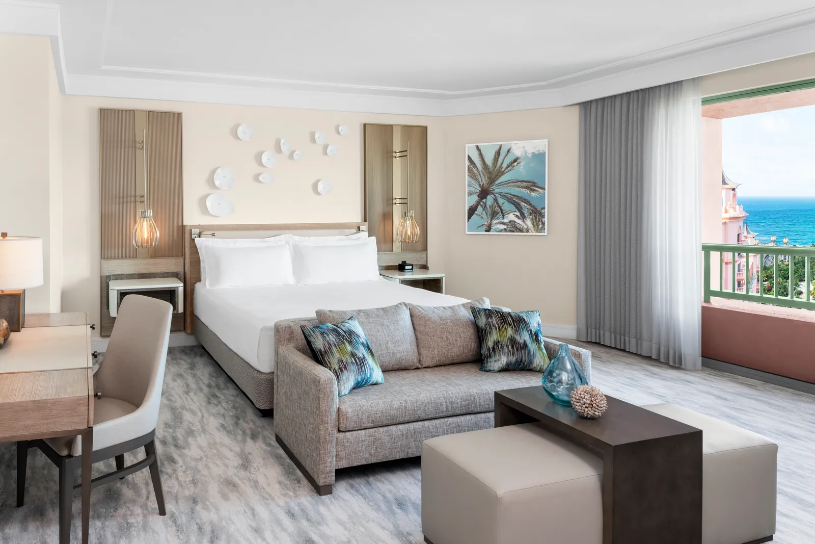 The bedroom of a Regal suite: a king bed, a sofa at its foot and a balcony with a sea view.