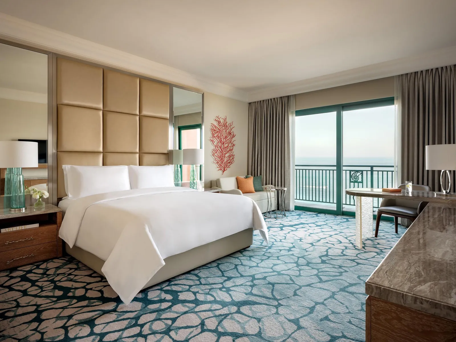 A king room with a padded headboard and a balcony over the sea