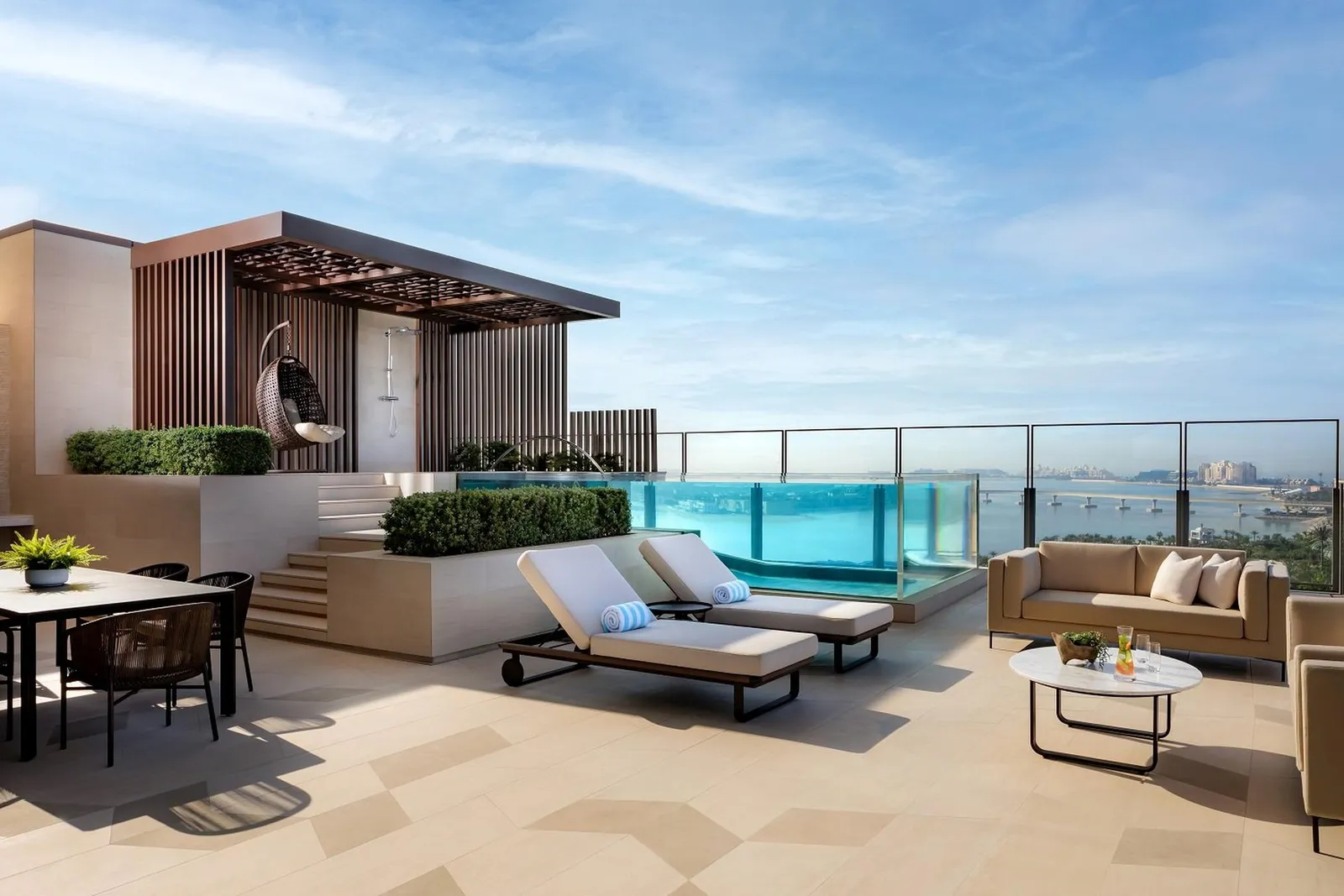 A terrace with a glass-sided private pool and the sea on the horizon