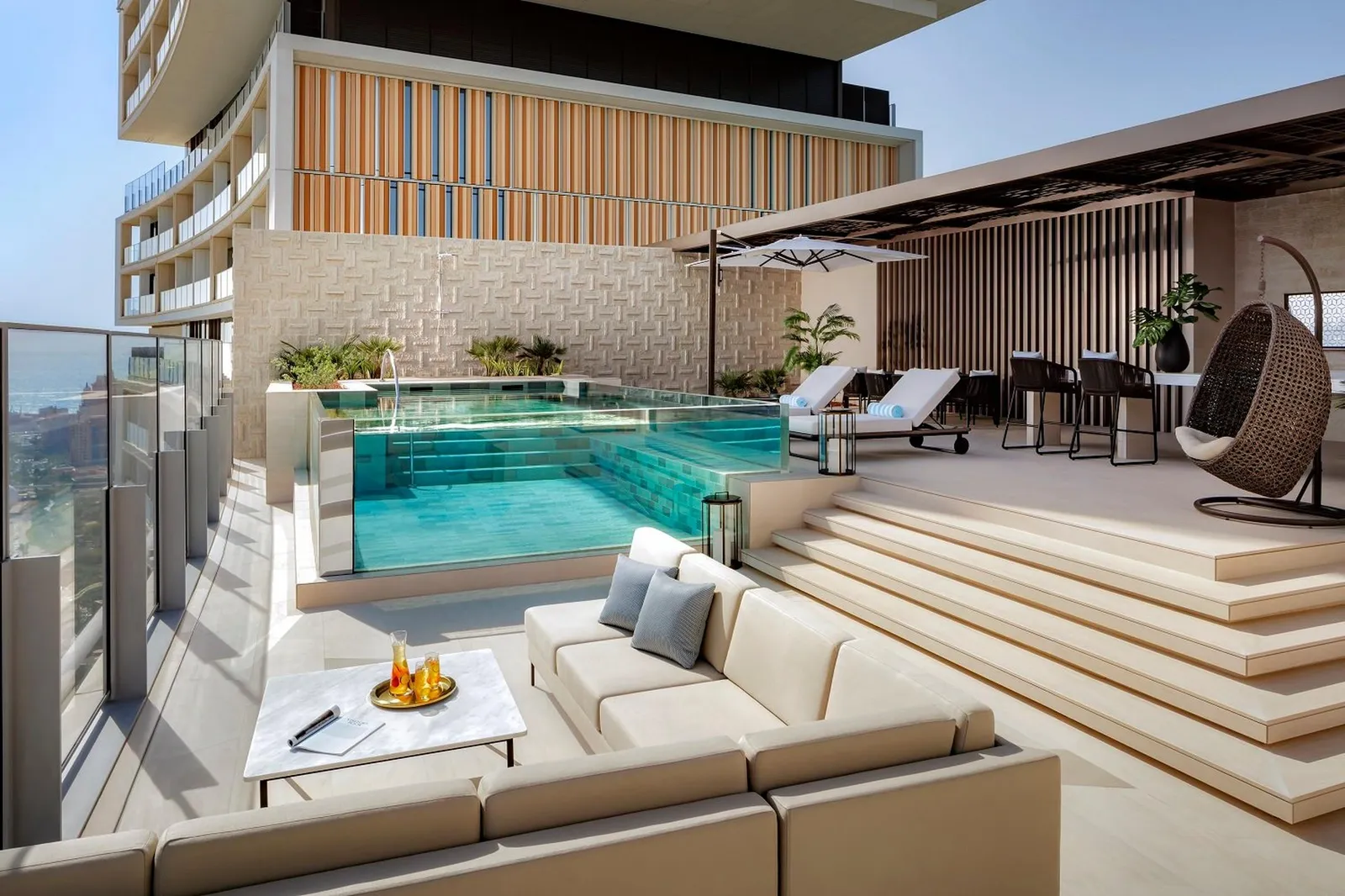 A penthouse terrace with a glass pool and sofas