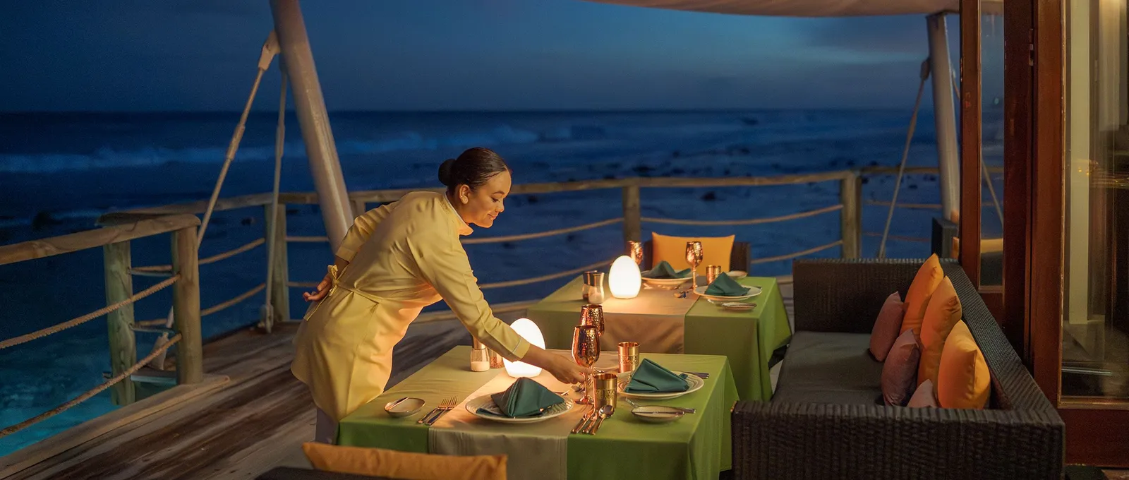 Just Veg over the water at dusk: a waitress lights the candles on the green tables