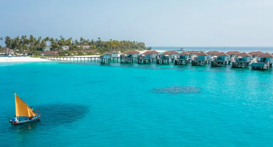 The yellow-sailed Ambaa dhoni off the water villas, over the reef.