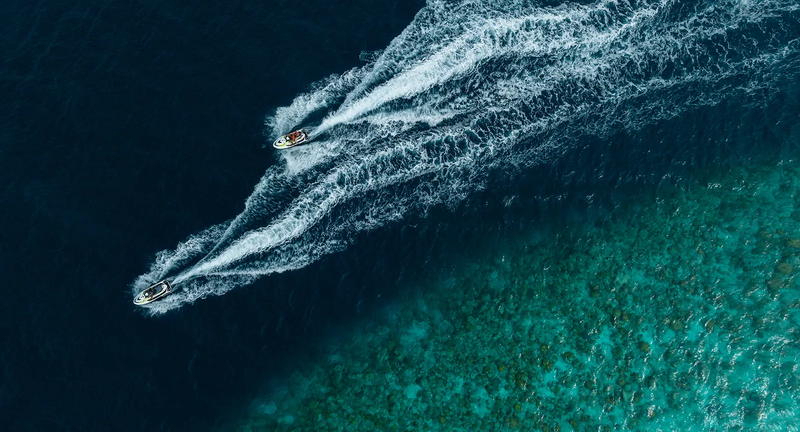 From above, a jet ski leaves a white wake on the blue water of the lagoon.