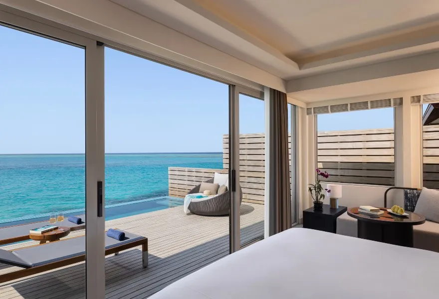 An Over Water Pool Villa bedroom, open onto the deck with its private pool and the sea.
