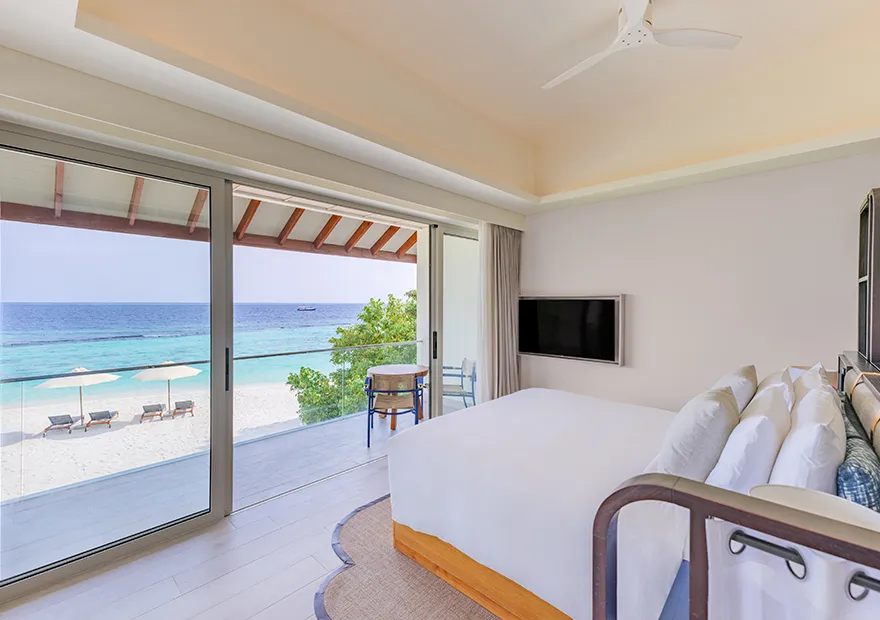 The Premium Ocean View Room: the bed facing the glass, the balcony and the sea beyond the beach.