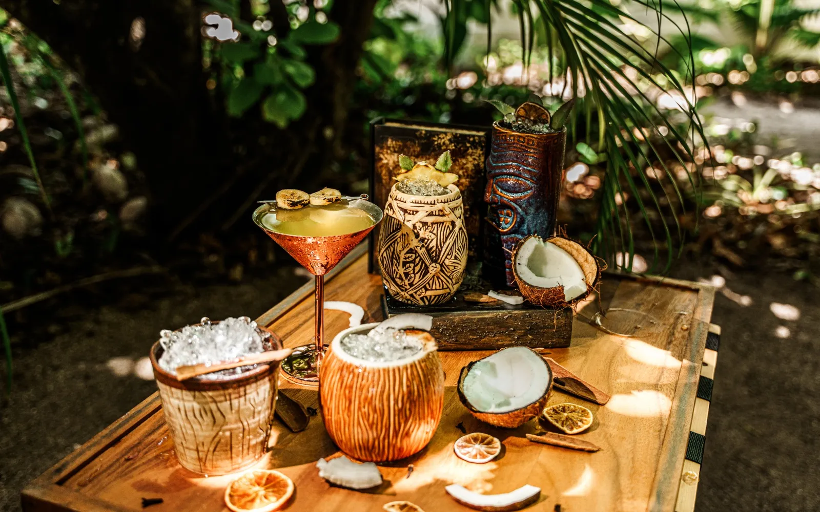 Cocktails in coconut cups and tiki glasses on a wooden table at Smugglers Shack.