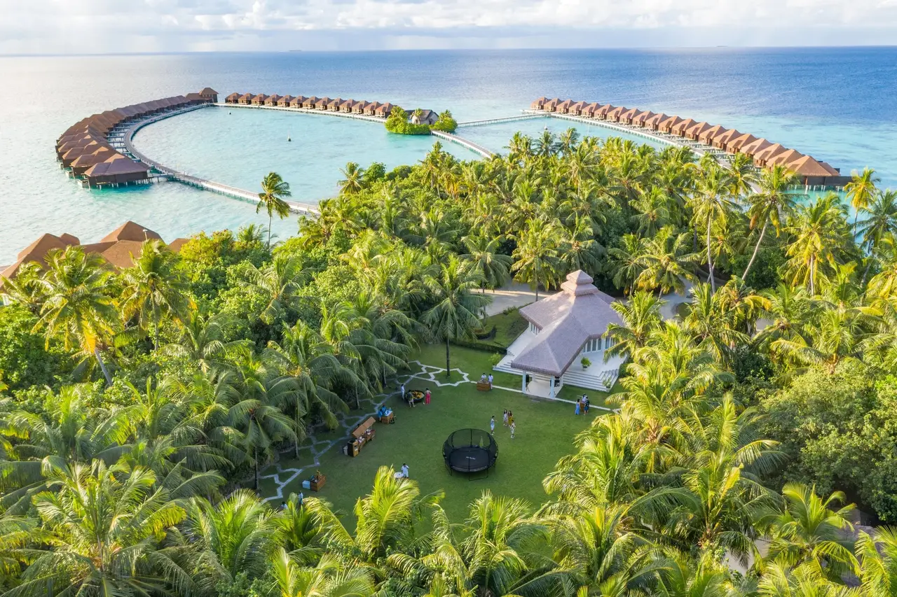 The island’s jungle from the air, the White Room’s lawn and the water villas beyond