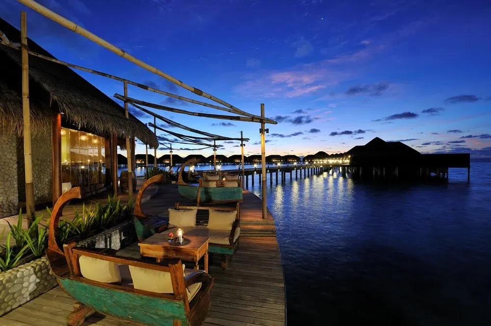Ile de Joie’s deck over the lagoon at dusk, the water villas beyond