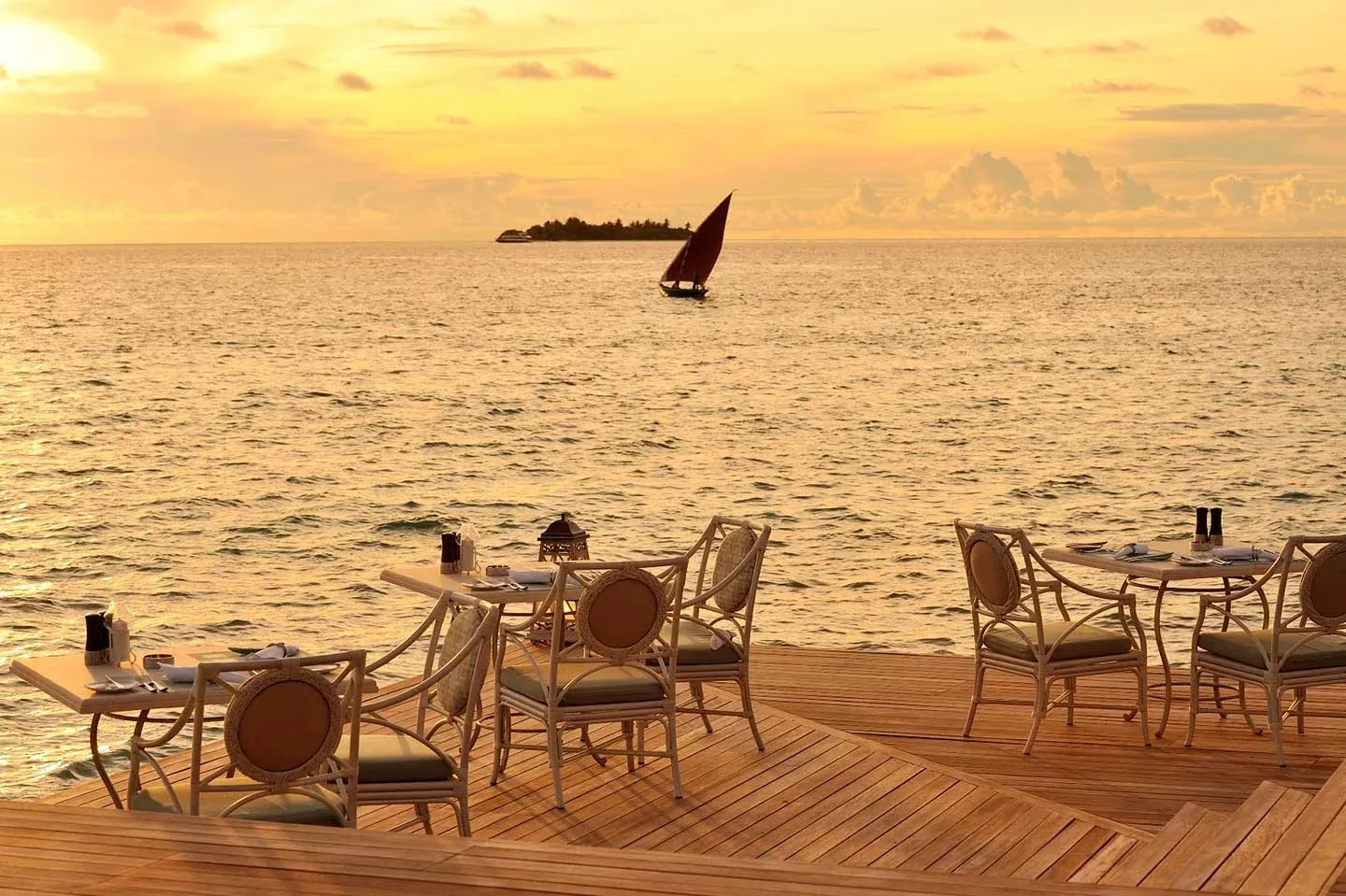 Ocean Breeze’s deck at sunset, a sail on a golden sea