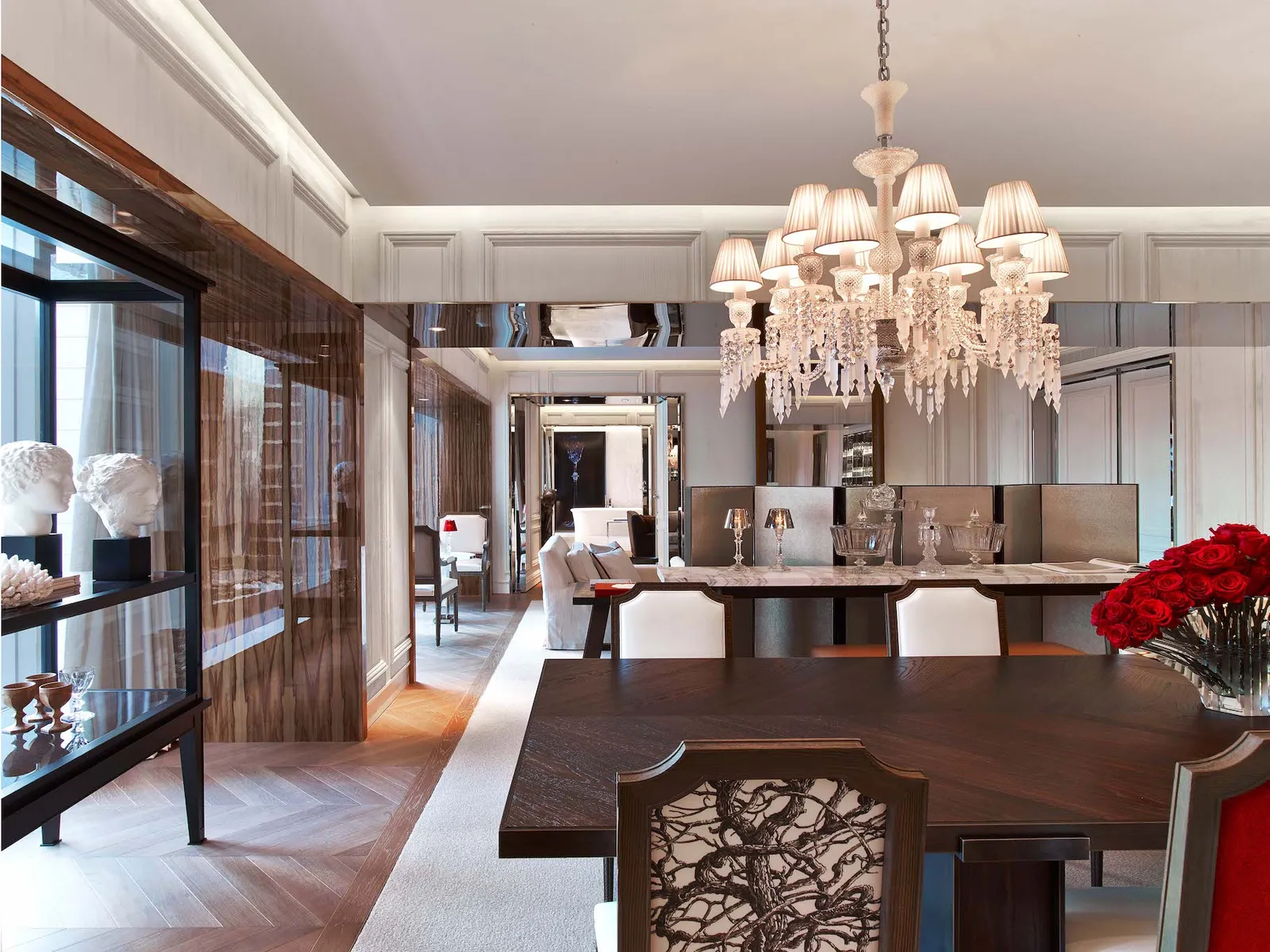 A dining table, crystal chandelier and polished wooden furniture