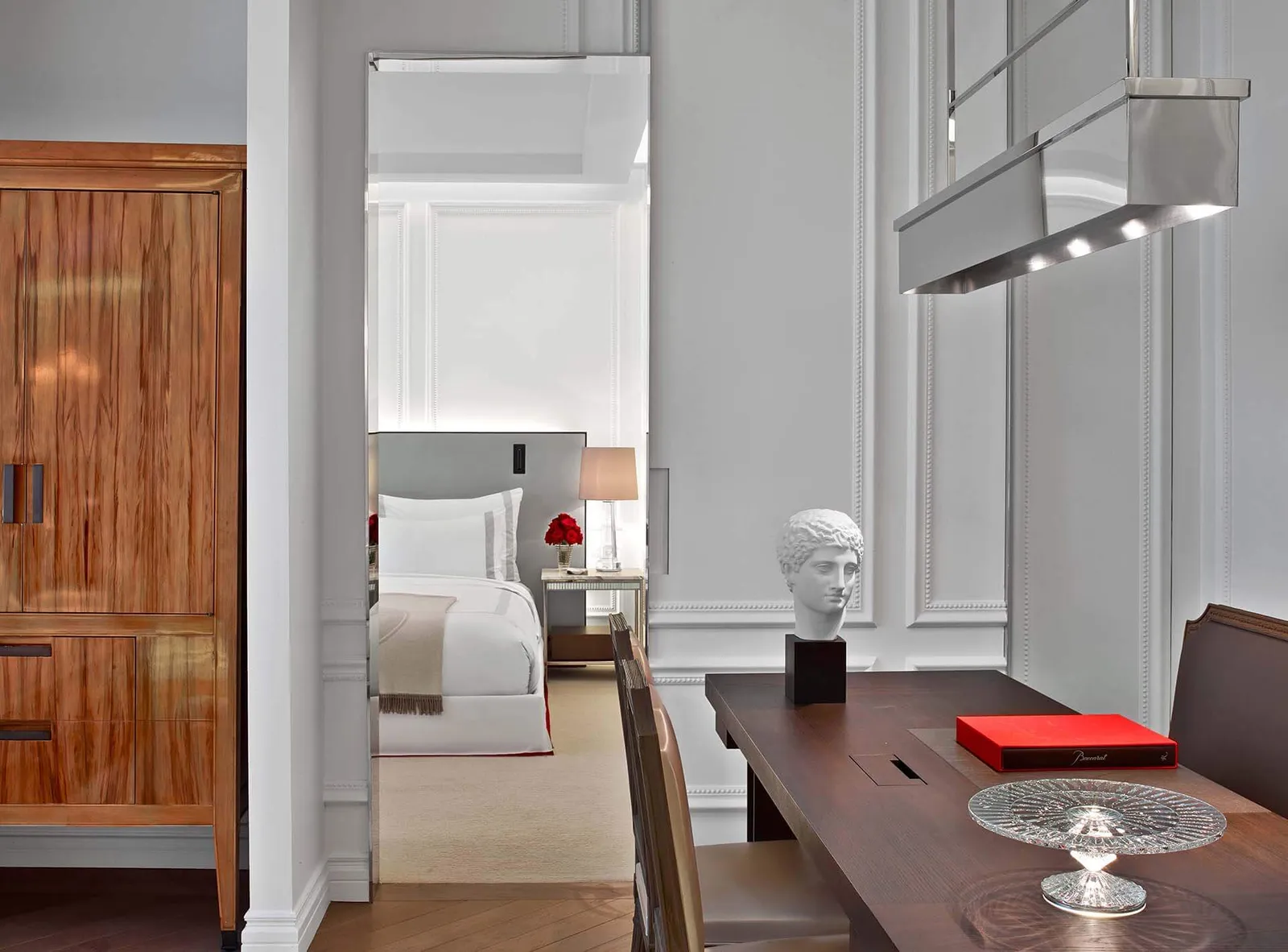 A desk, wooden wardrobe and opening into a bedroom