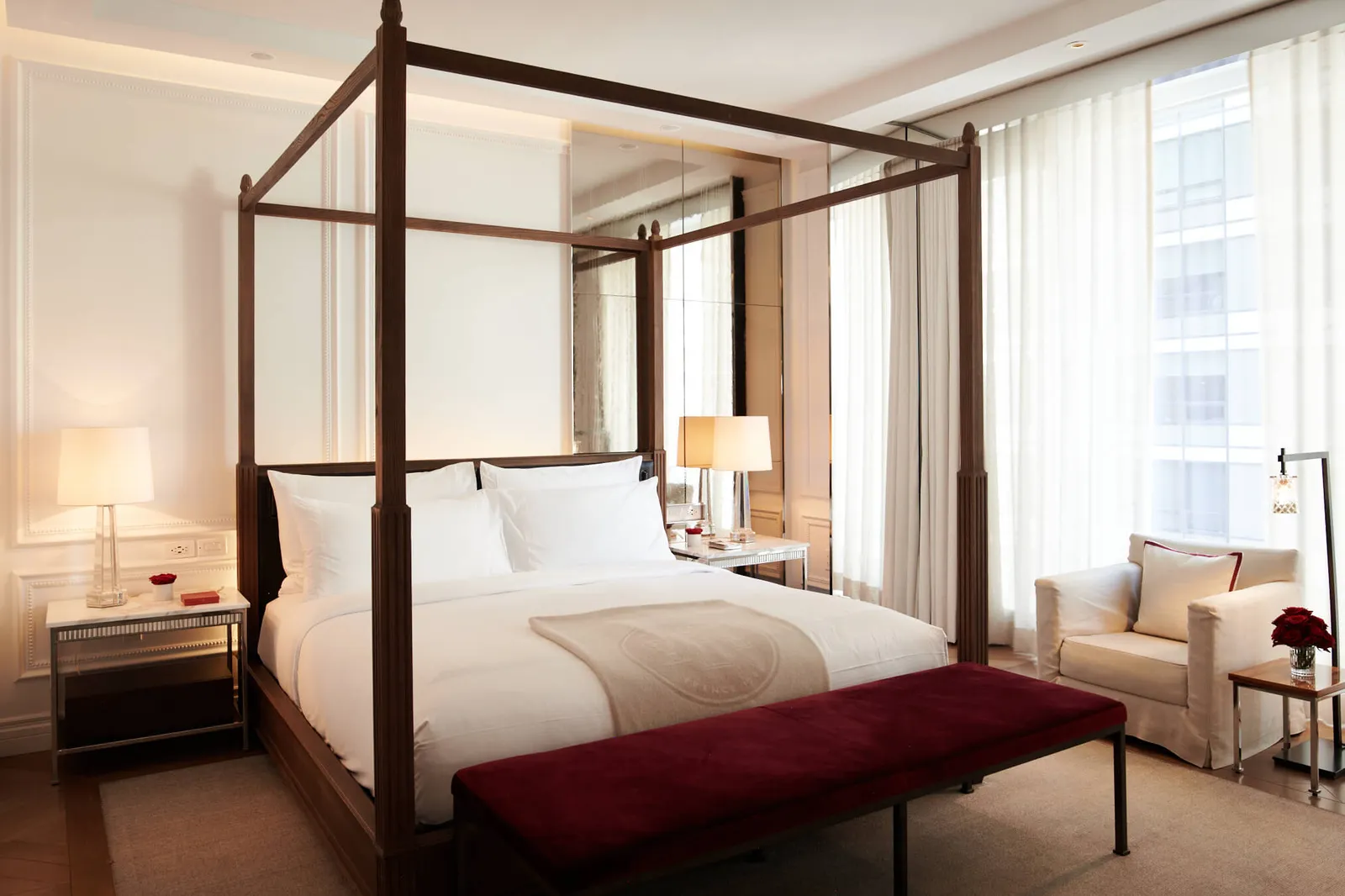 A four-poster bed and white armchair beside a window