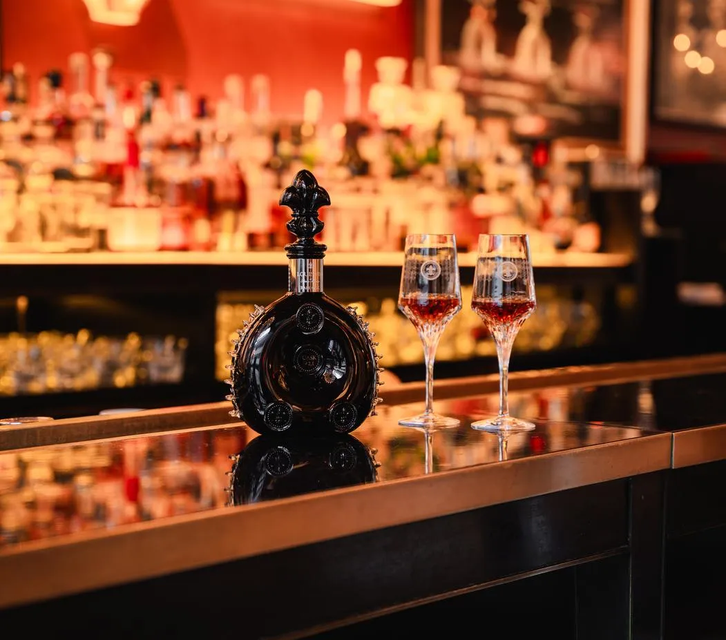 A cognac bottle and 2 glasses on the bar counter