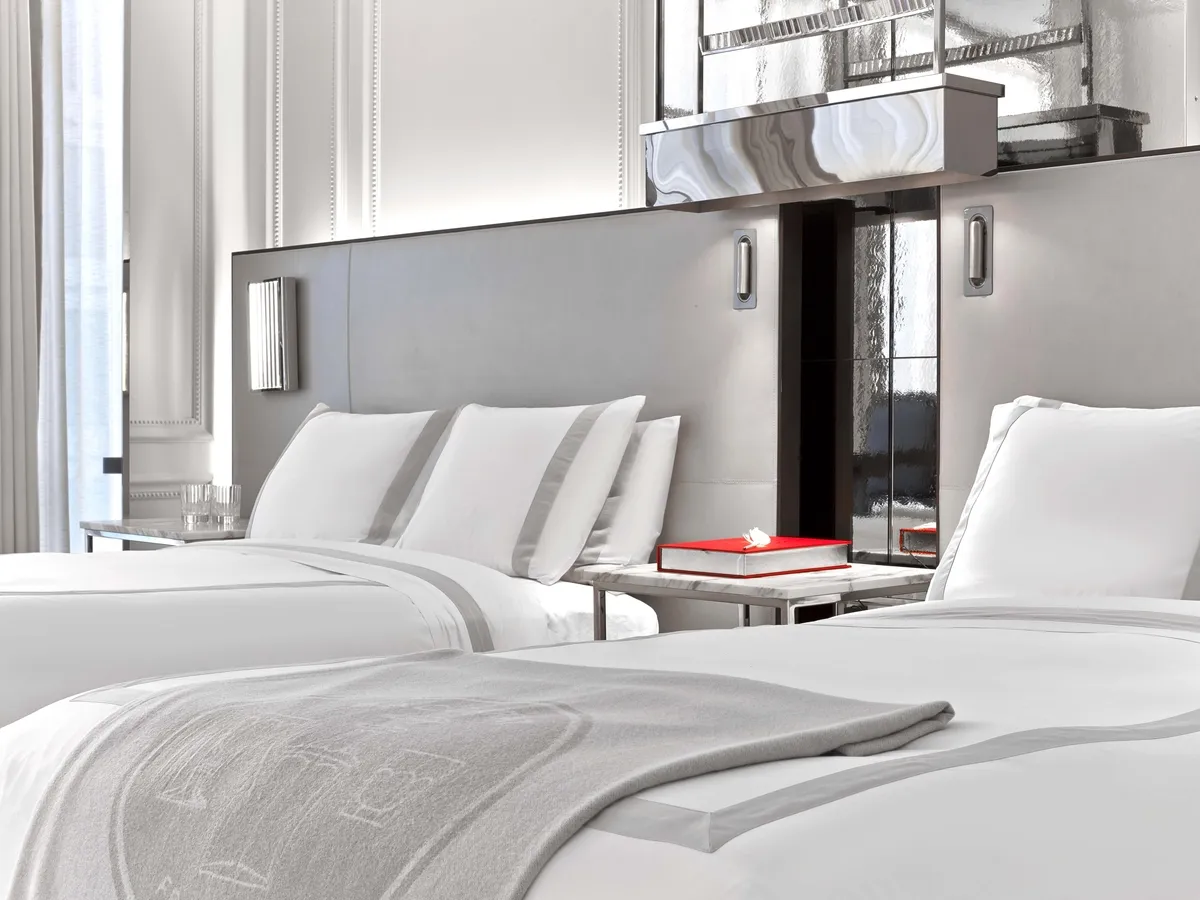 2 double beds with pale headboards and a bedside table between them