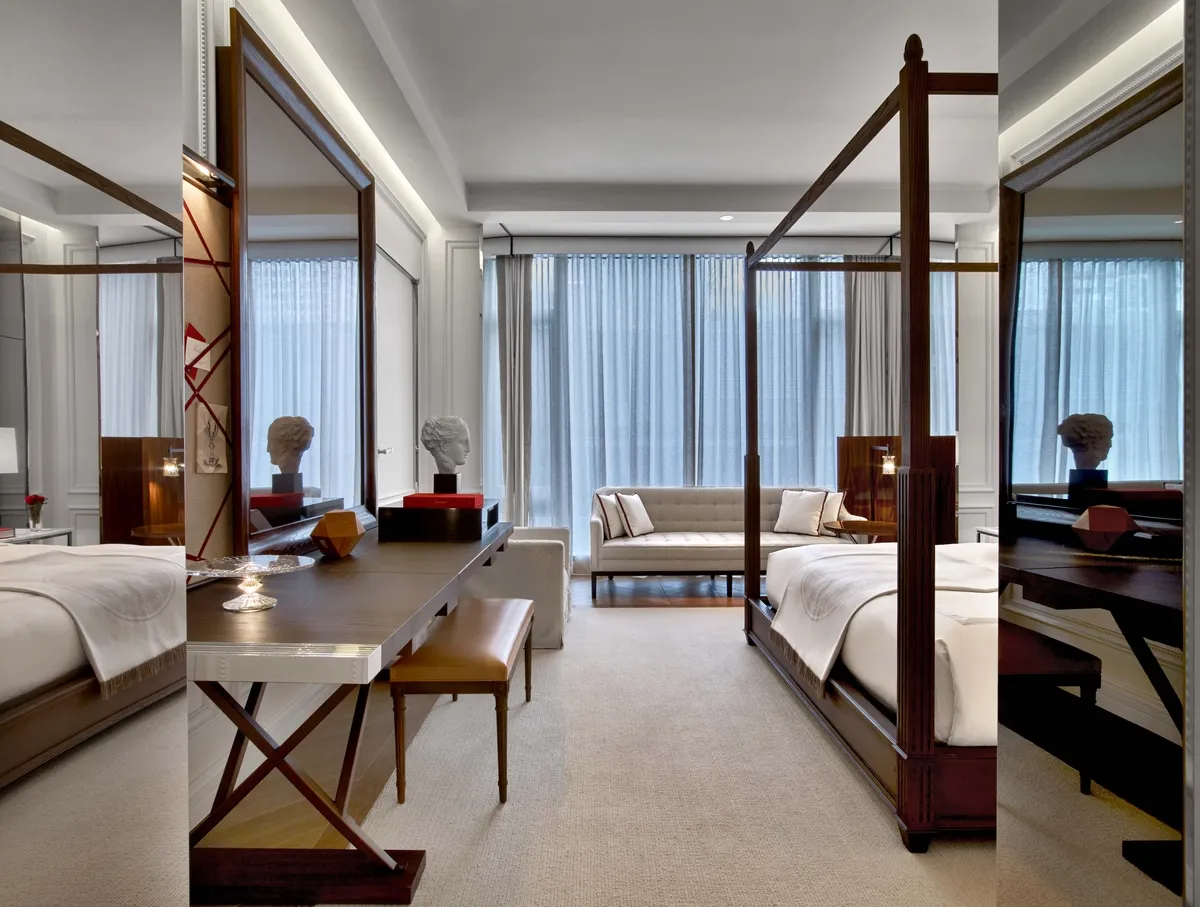 A mirrored desk, four-poster bed and sofa beside the windows