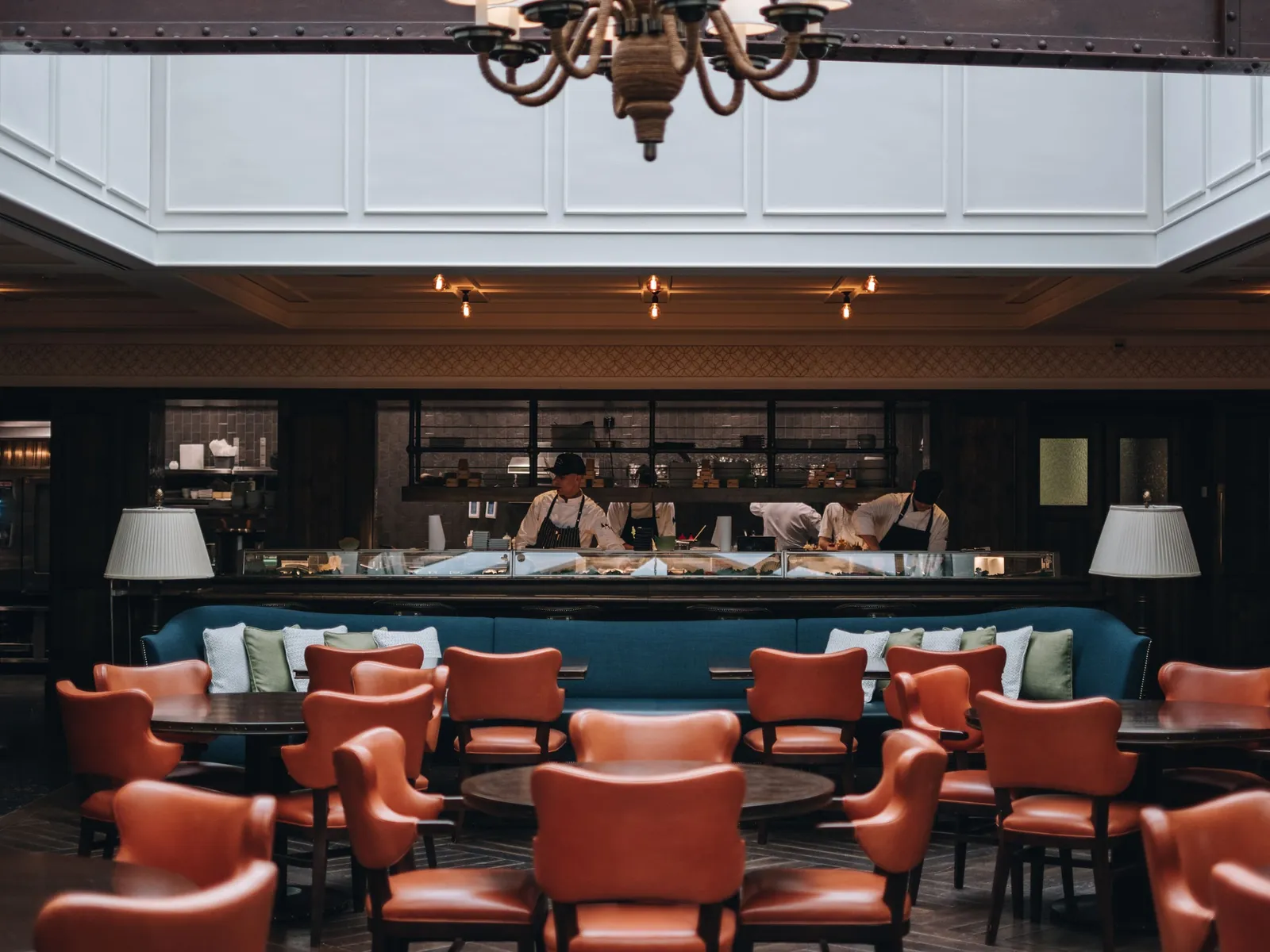 La Coupole – Matsuhisa: tan leather armchairs around the tables, the counter with chefs at work and the white panelled ceiling.